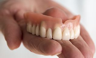 Hand holding full dentures