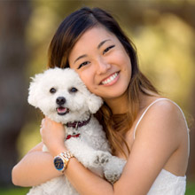 Woman with bright white smile hugging her dog